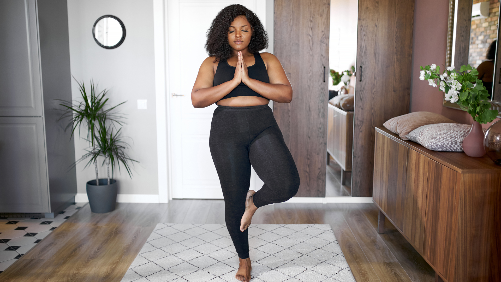 Young woman practicing balance, stand on one leg in a variation of Tree Pose. 