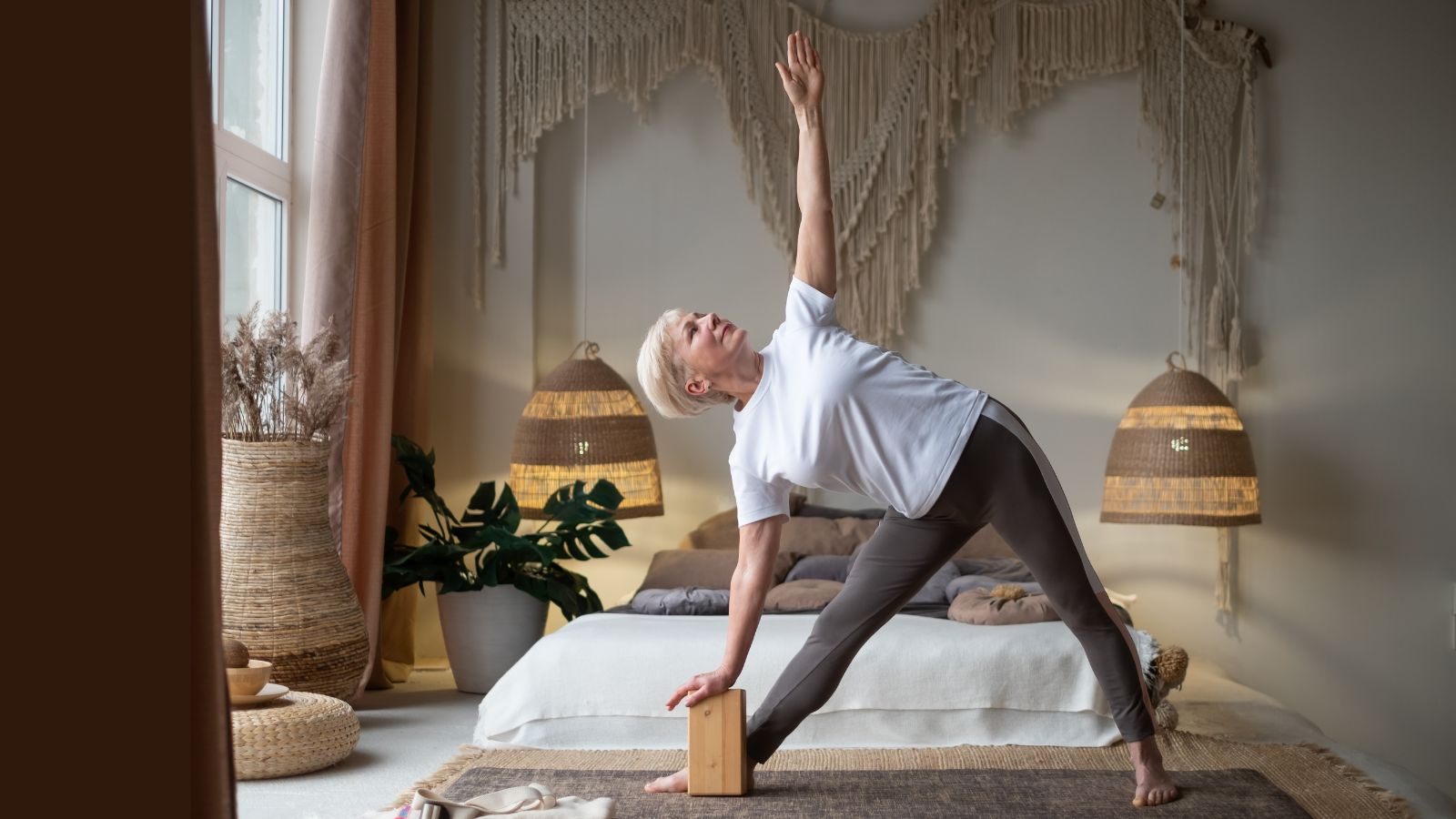 Senior woman practicing yoga, stretching in Utthita Trikonasana Pose or Extended Triangle Pose, working out at home