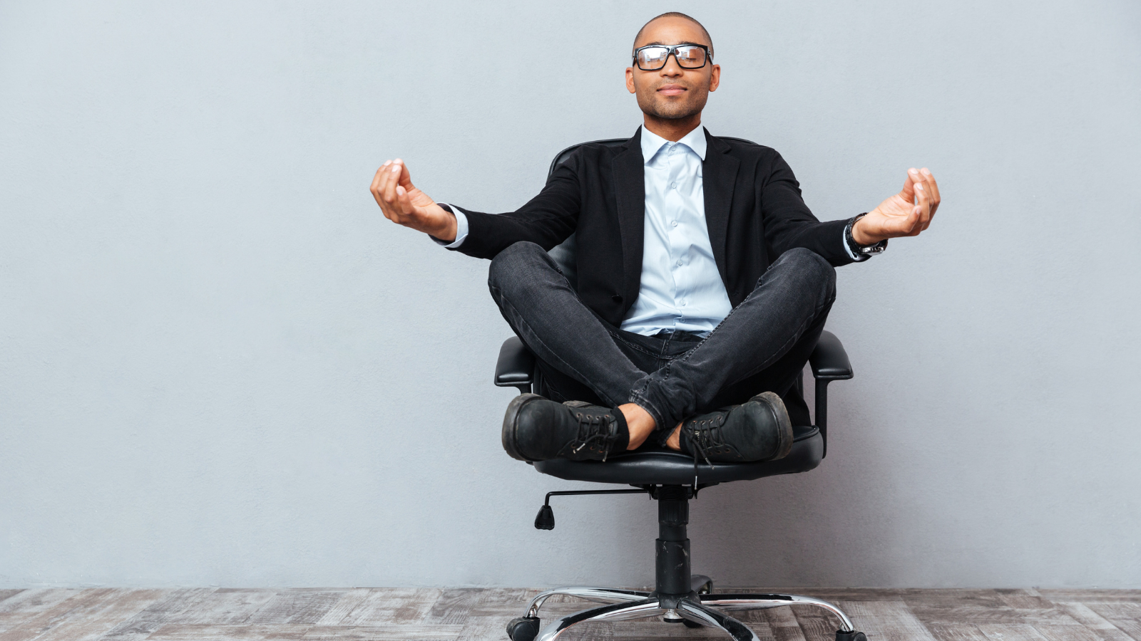 Relaxed handsome young man sitting and meditating on office chair