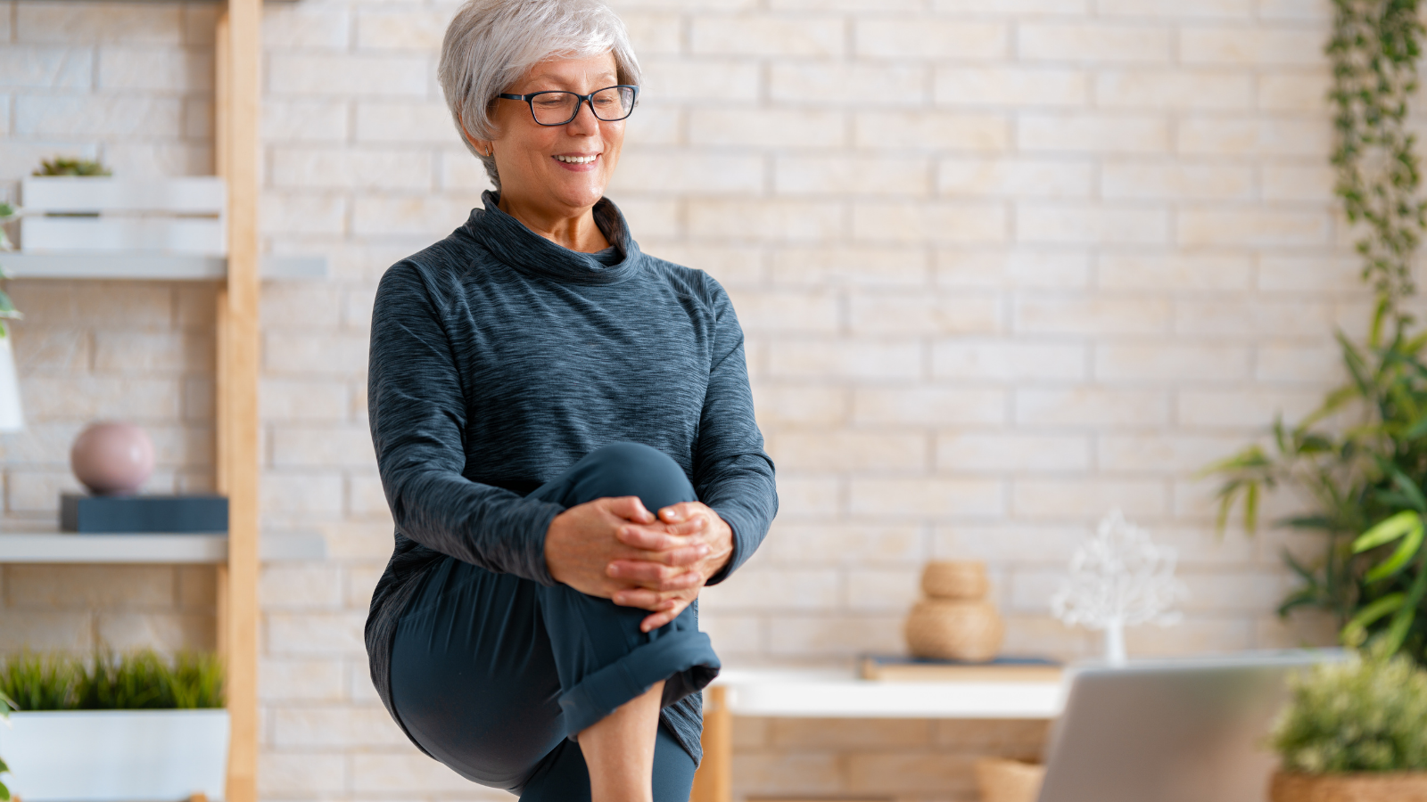 Senior woman in activewear watching online courses on laptop while exercising at home