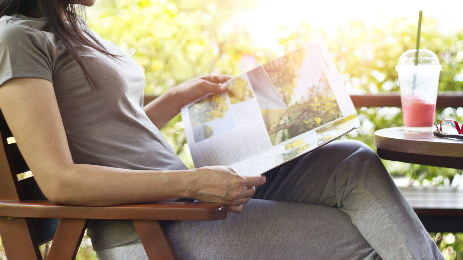 Woman relaxing by reading magazines also enjoying a strawberry smoothie