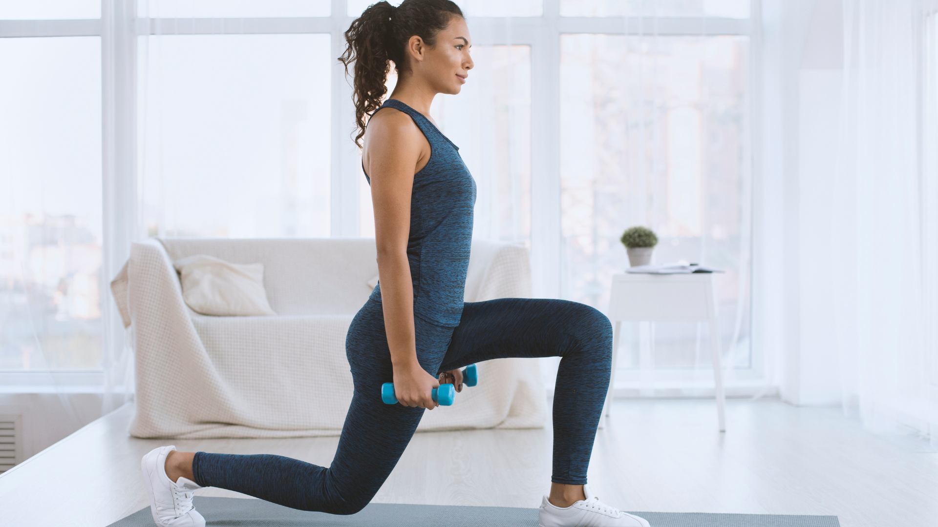 Sporty yogi practicing lunges with dumbbells at home.