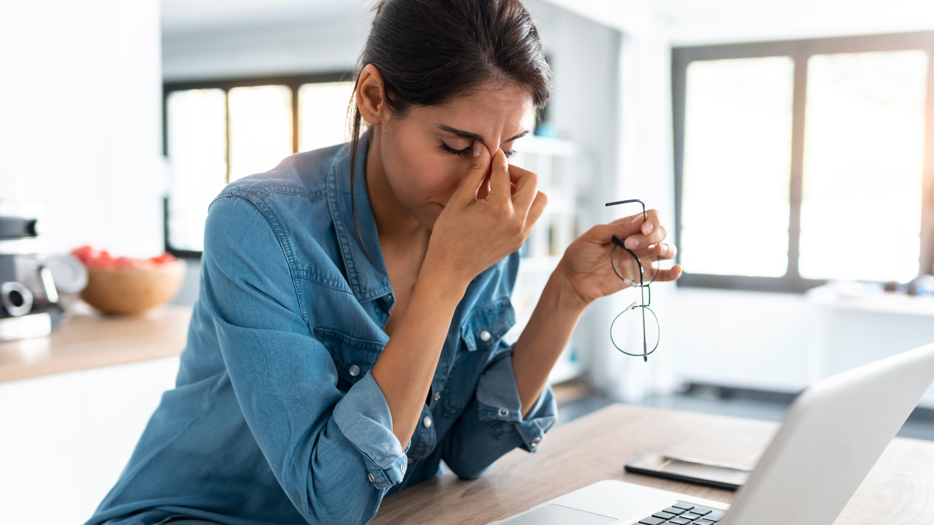 Shot of stressed business woman working from home on laptop looking worried, tired and overwhelmed. 