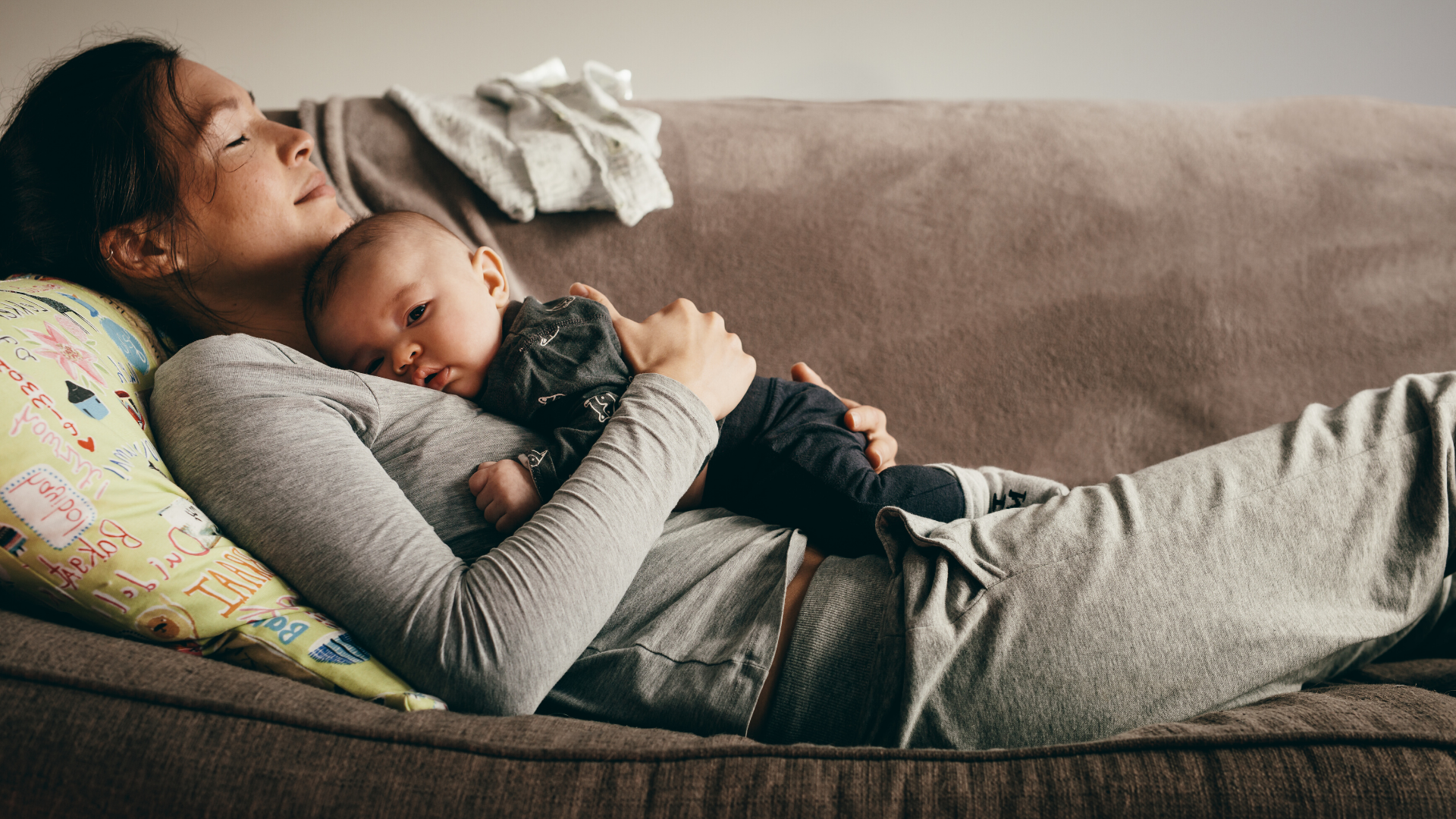 Mom and baby resting on couch together.