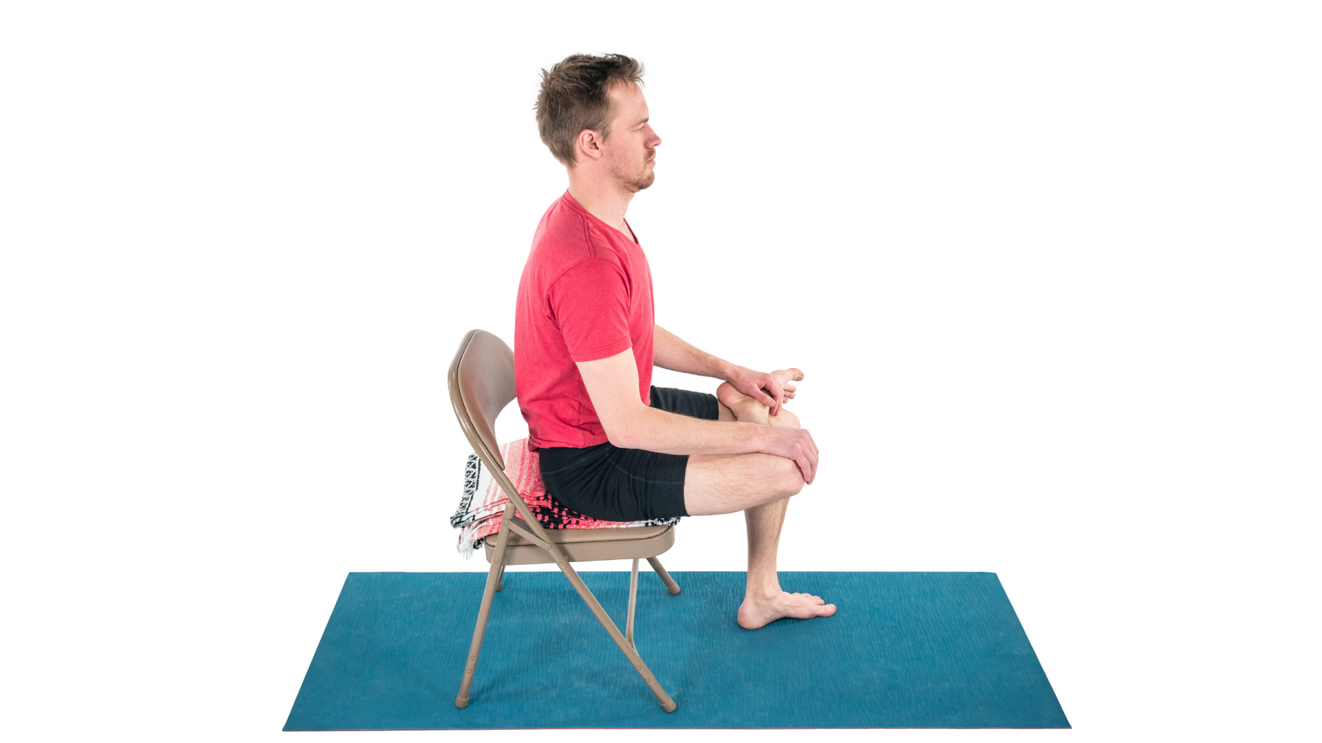 Man practicing yoga seated figure four stretch.