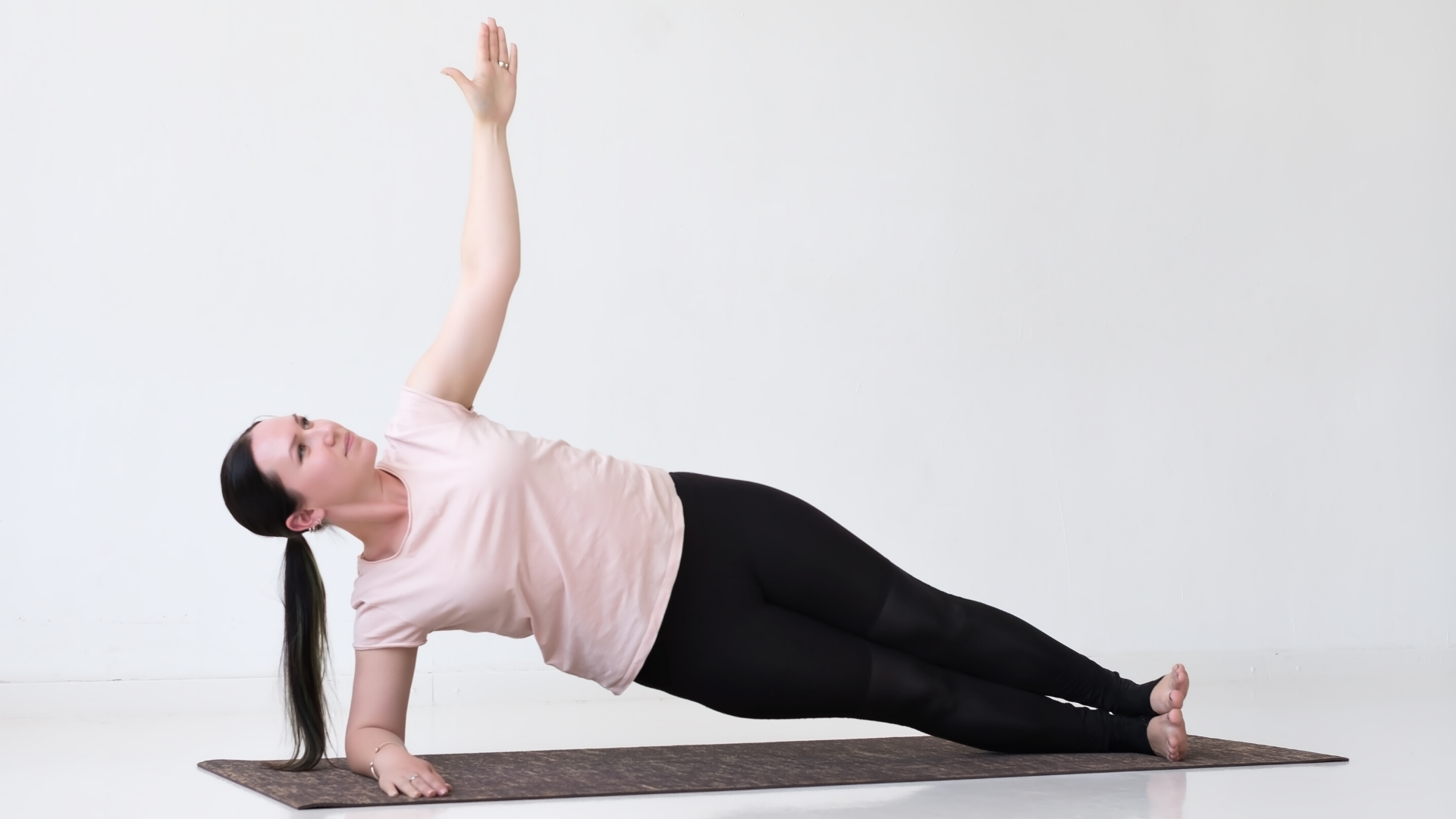 Yoga student practicing yoga side plank Vasisthasana on her forearm.