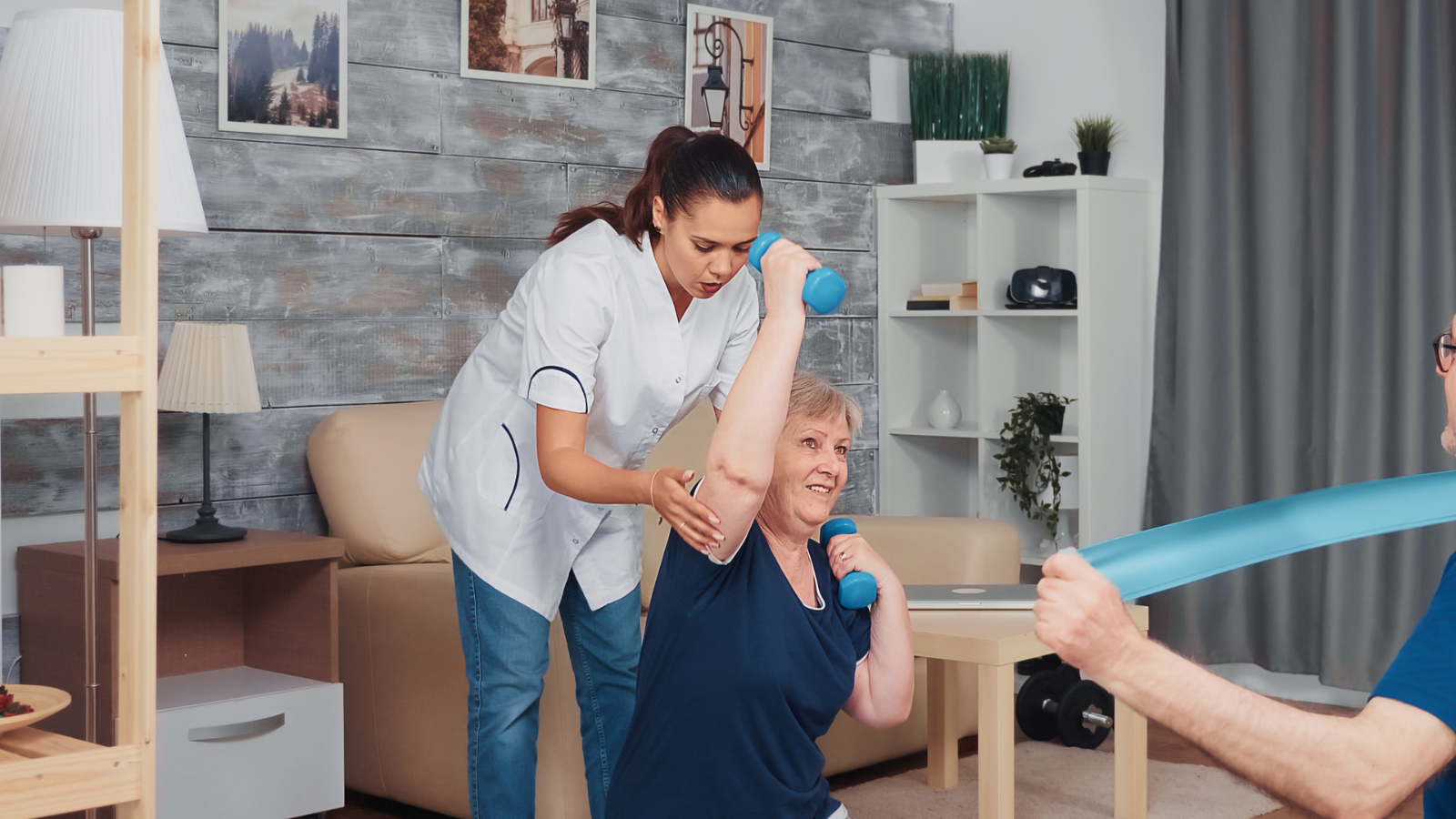 Senior couple exercising with therapist on yoga mat at home. Home assistance, physiotherapy, healthy lifestyle