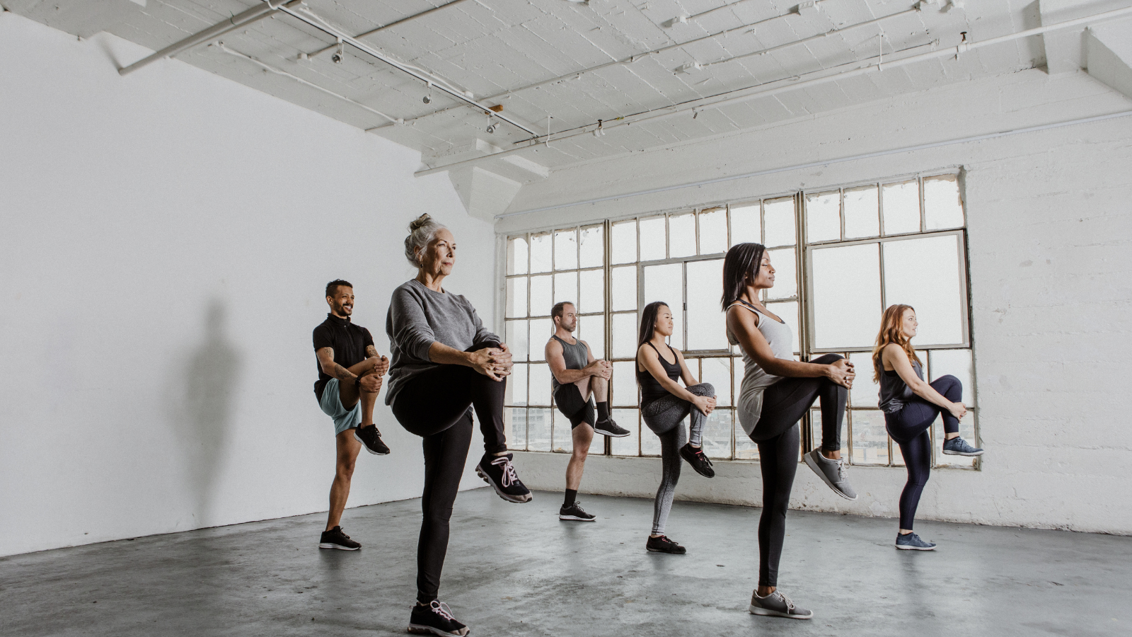  Diverse people stretching their knees and practicing balance in a yoga class