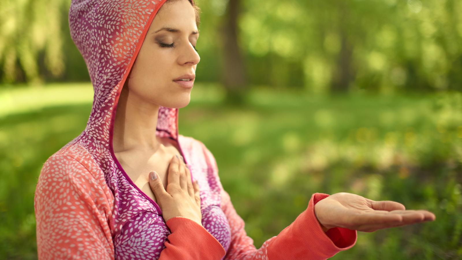 Portrait of beautiful middle eastern girl meditating and doing yoga at sunset on the grass in a park or forrest.