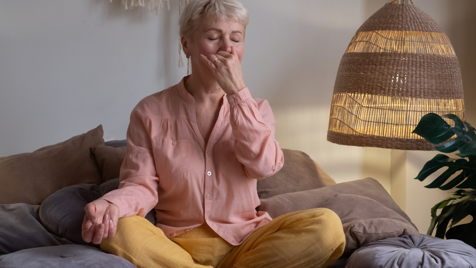 Senior woman practicing yoga at home, making Alternate Nostril Breathing exercise, nadi shodhana pranayama pose, working out