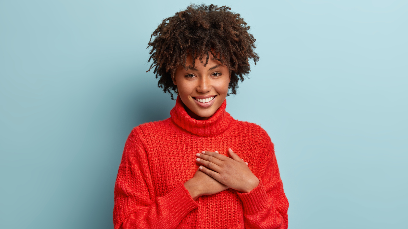  Photo of emotional female touching her heart with both palms, demonstrates thankful gesture.