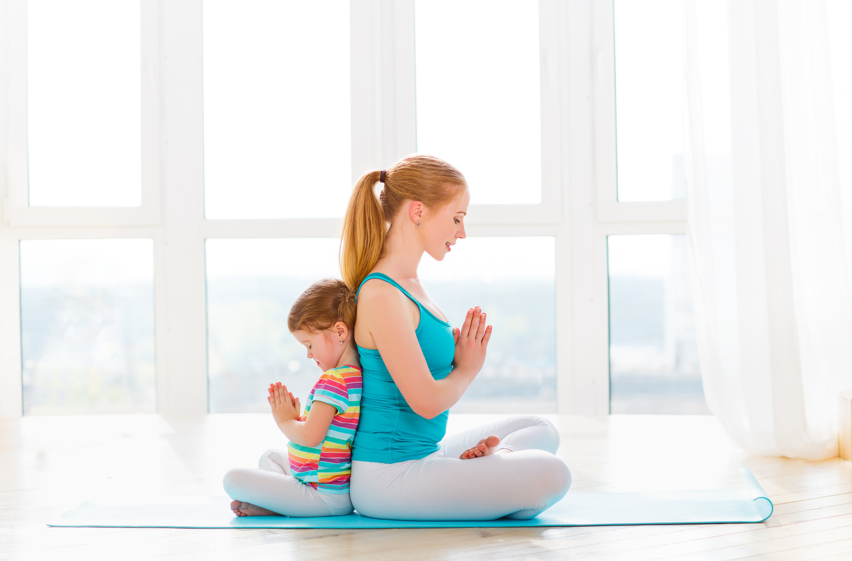 Parent and child practicing yoga together in cross-legged pose