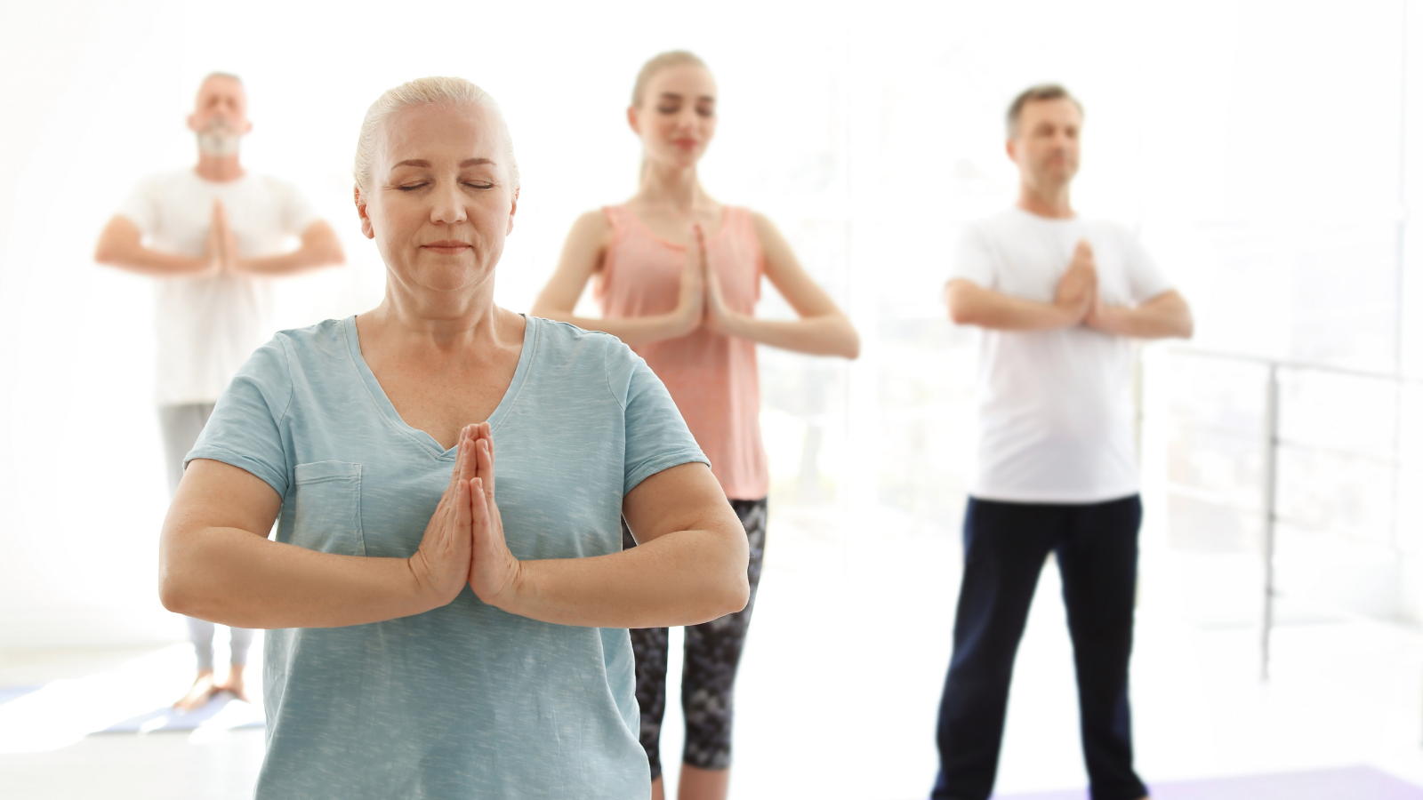 Group of diverse people in sportswear practicing yoga indoors.