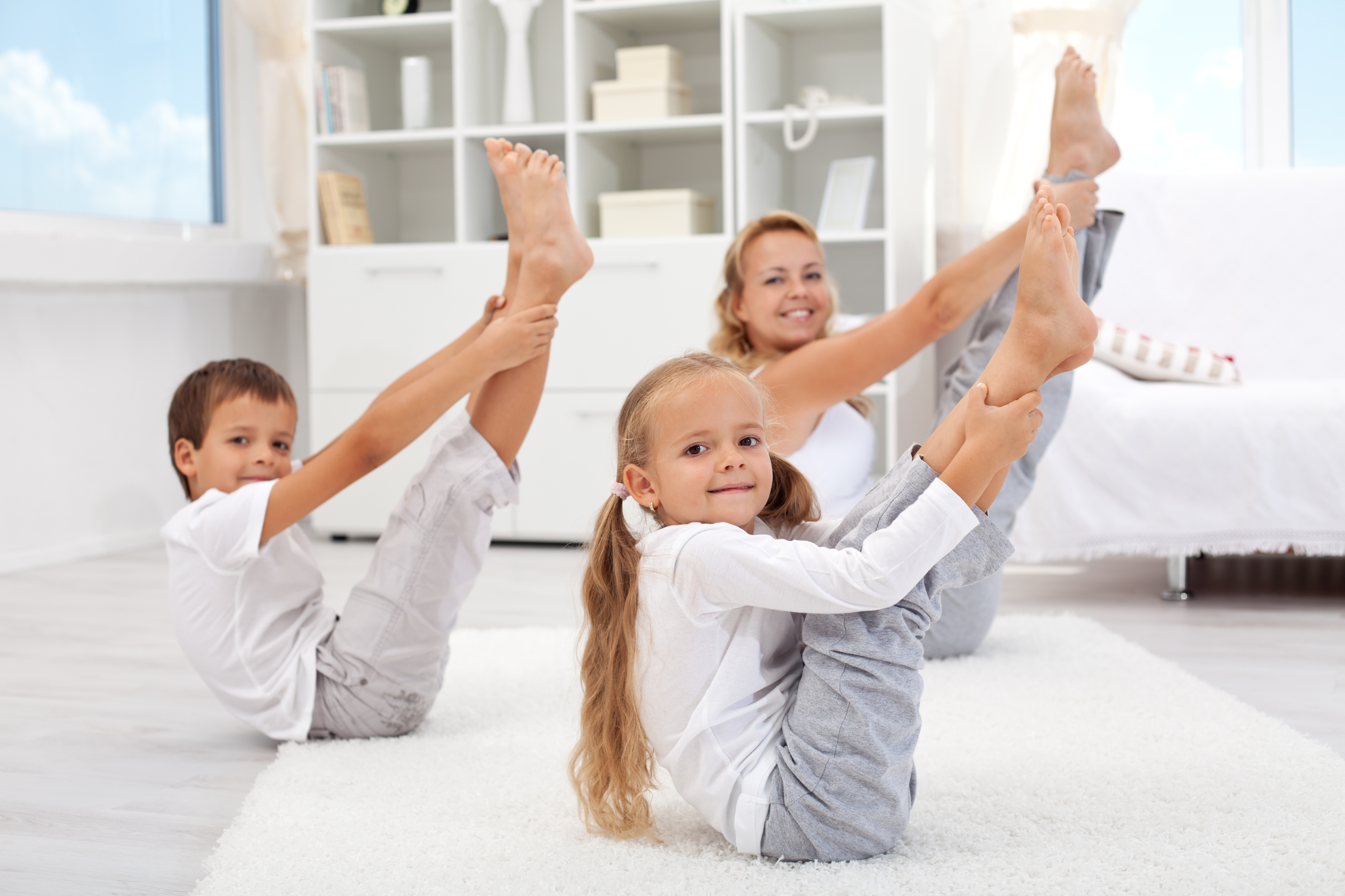 Mother and children practicing yoga together in Boat Pose (Navasana)