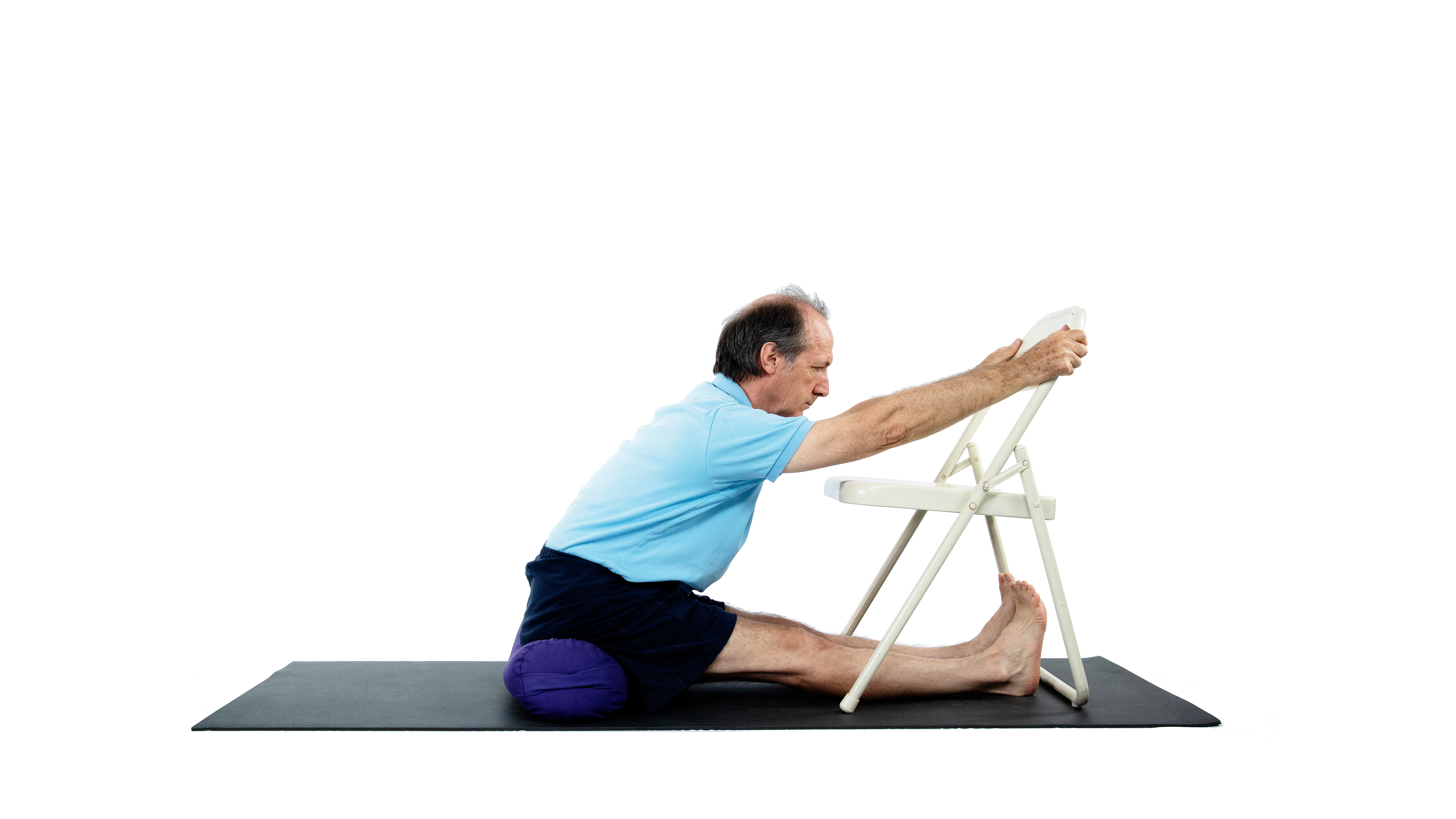 Seated Forward Fold Paschimottanasana with chair and bolster used as props for this variation