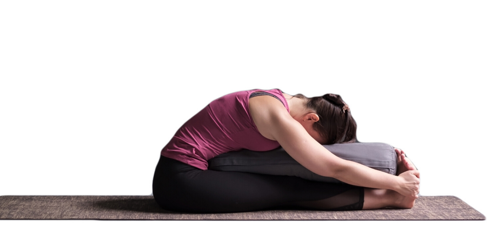 Female yoga student practicing seated forward bend (paschimottanasana) 