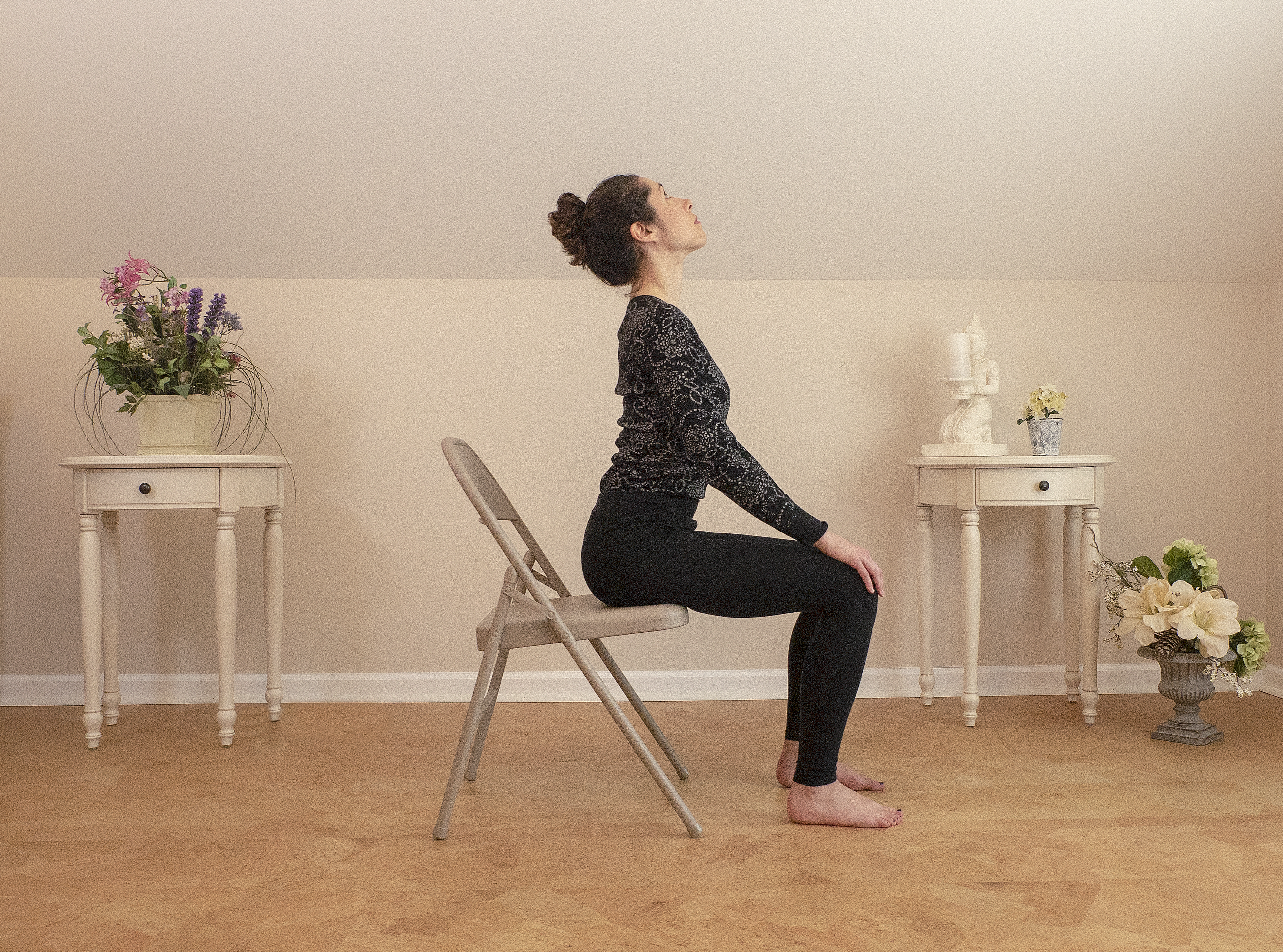 woman practicing cow pose (Bitilasana) yoga in a chair