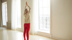 mature woman with short gray hair doing sun salutation Arms Overhead Pose or Urdhva Hastasana