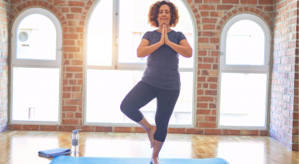 Older woman in yoga studio practicing Tree Pose (Vrksasana)