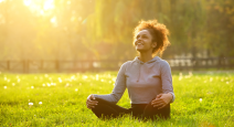Happy young woman sitting outdoors in yoga's Easy Pose resting and enjoying nature.