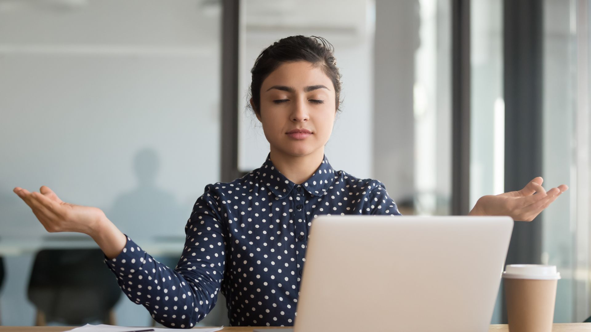 A woman takes a moment at work to meditate and calm herself. 