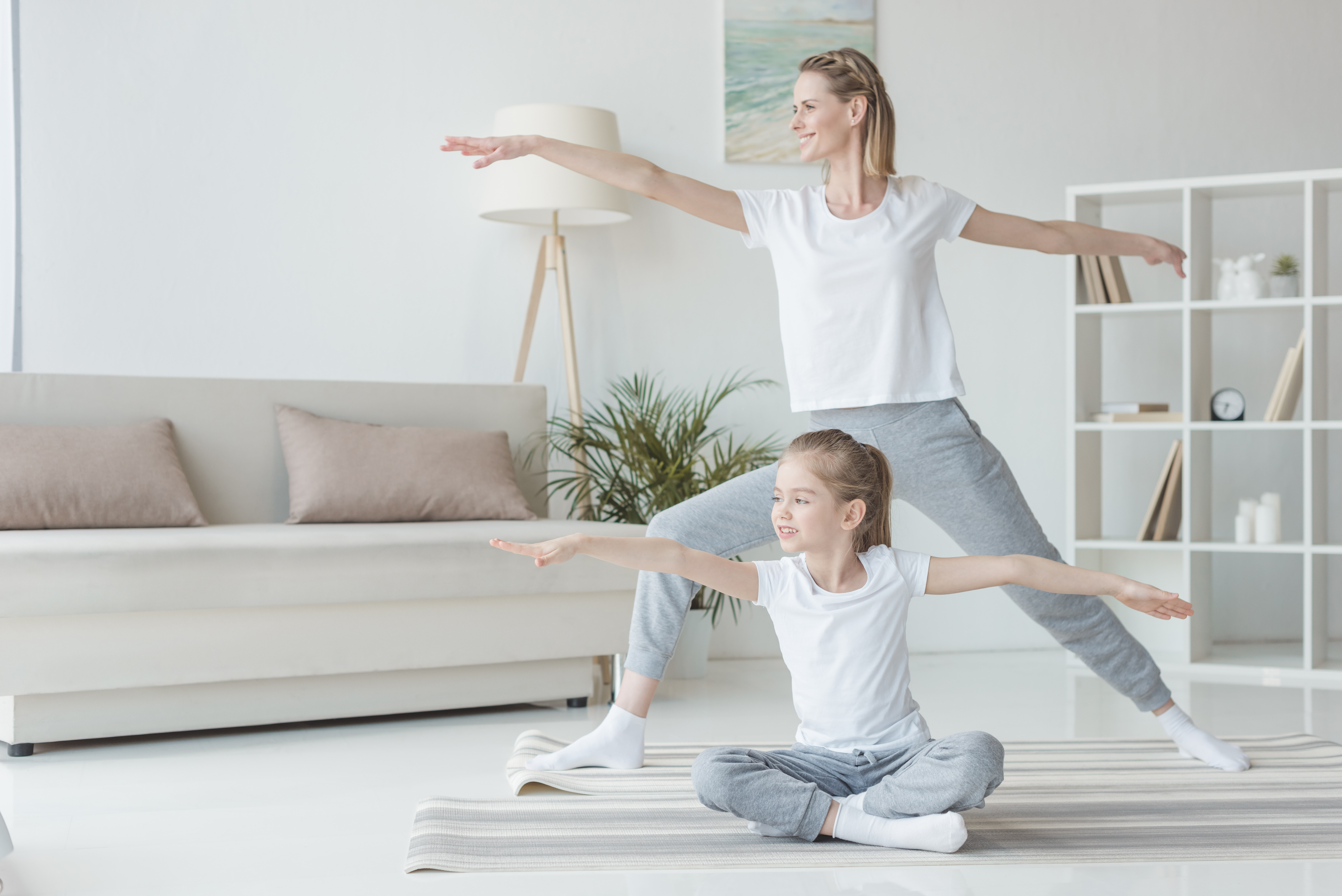 A mother and child practicing yoga together in Sun Saluting Warrior poses and variations